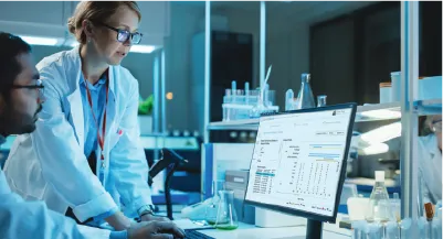 women standing at desk next to monitor