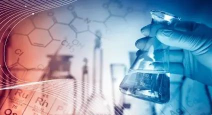 A hand wearing a blue latex glove holding a beaker 