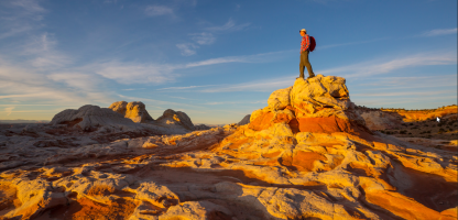 man on rock on right side with back side to us, rolling red rock 