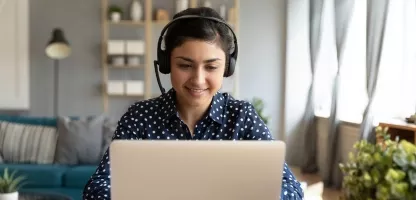 Woman at home with a headset on looking at a laptop