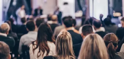 A group of people watching a live conference meeting in a conference hall