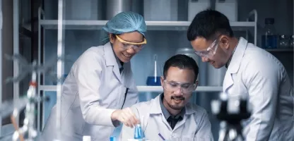Three chemists in white coats in a laboratory doing science