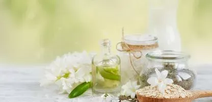 white flowers, a bottle of perfume, wooden spoon of oats, jar of dried flowers