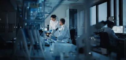Modern Medical Research Laboratory_ Two Scientists Working, Using Digital Tablet, Analyzing Test, Talking. Advanced Scientific Pharmaceutical Lab for Medicine, Biotechnology Development. Evening Time.webp