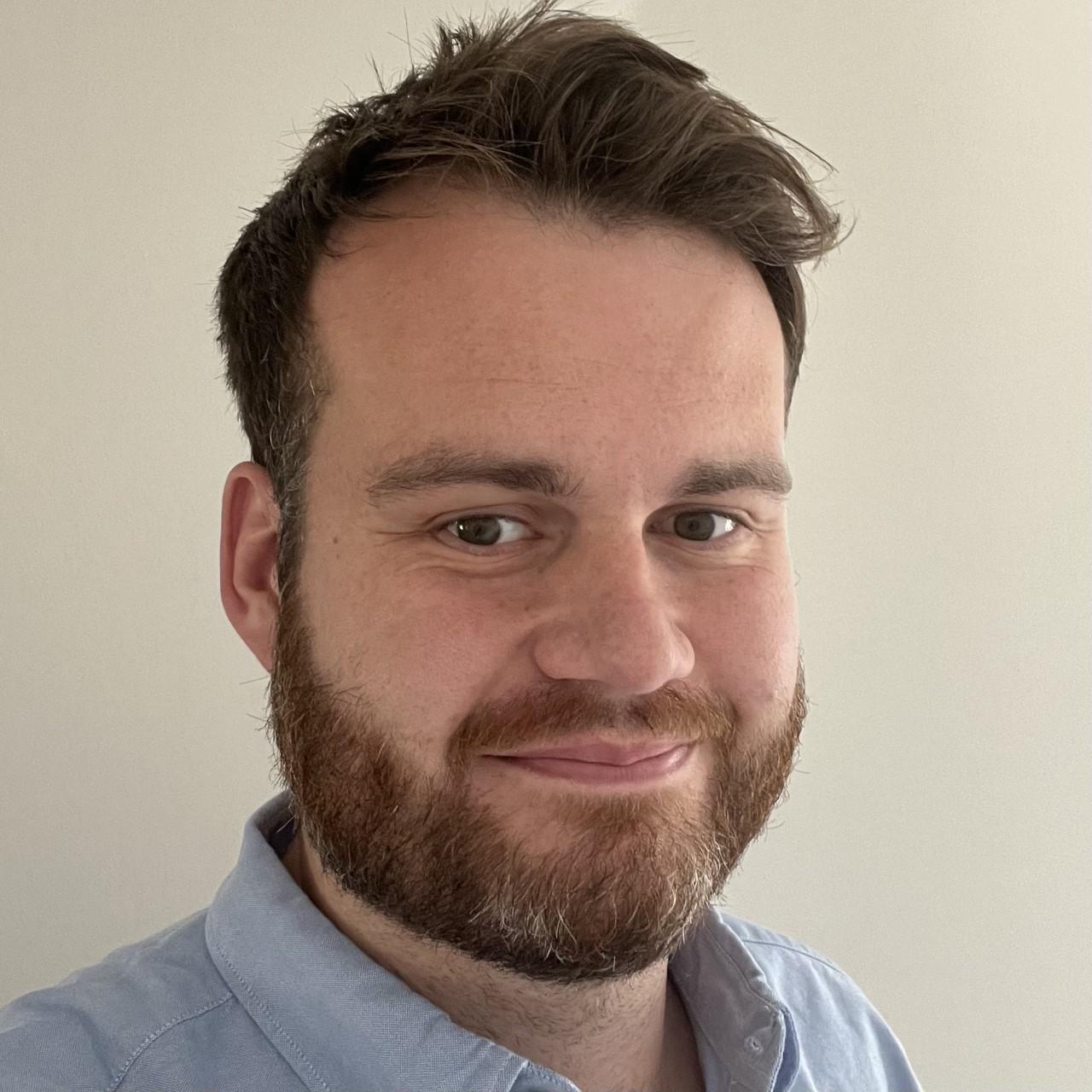 Chris Rundell headshot, male, light brown hair with a beard and mustache, green-brown eyes