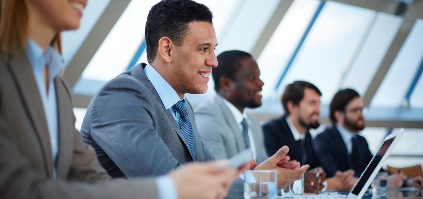 Woman, man, and three other men in a row with lap tops at a conference